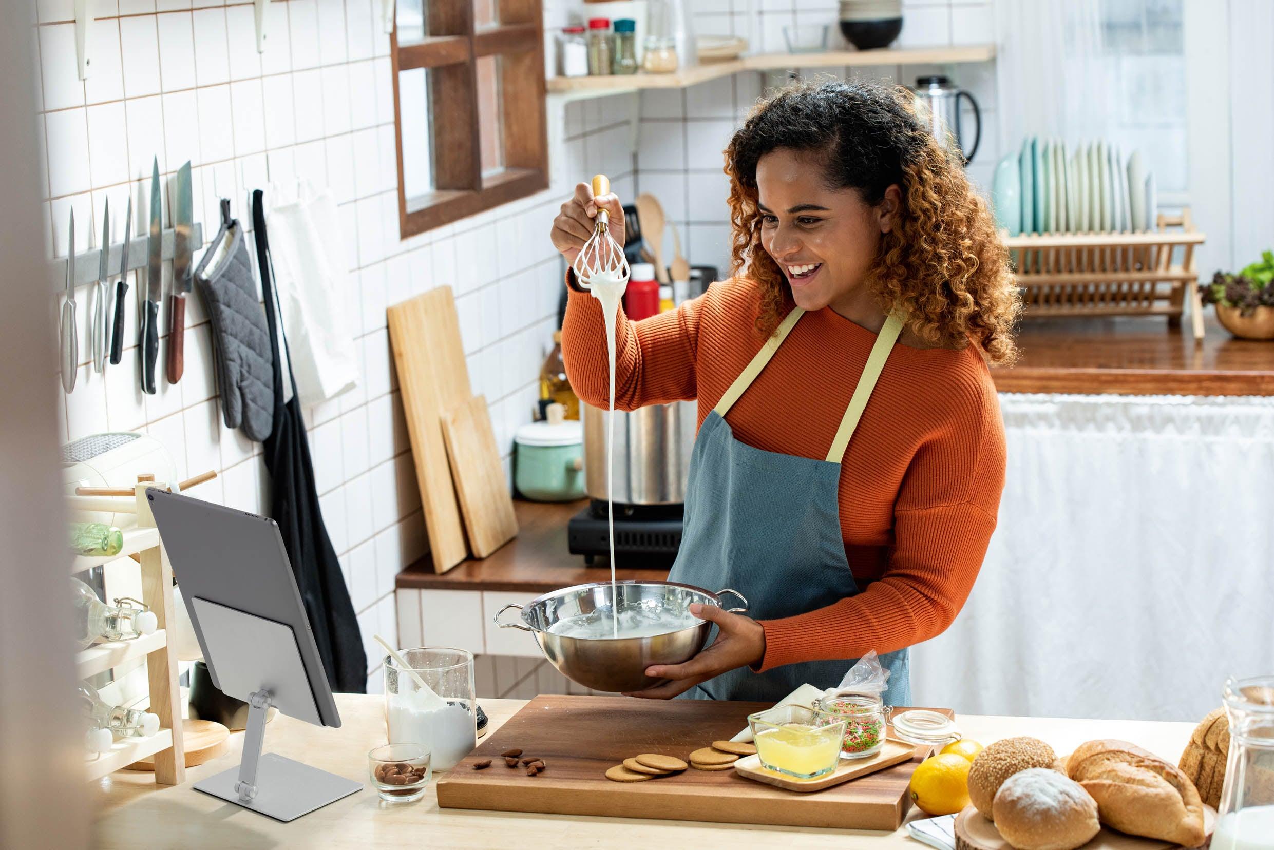 Woman using a tablet holder whilst baking in the kitchen.